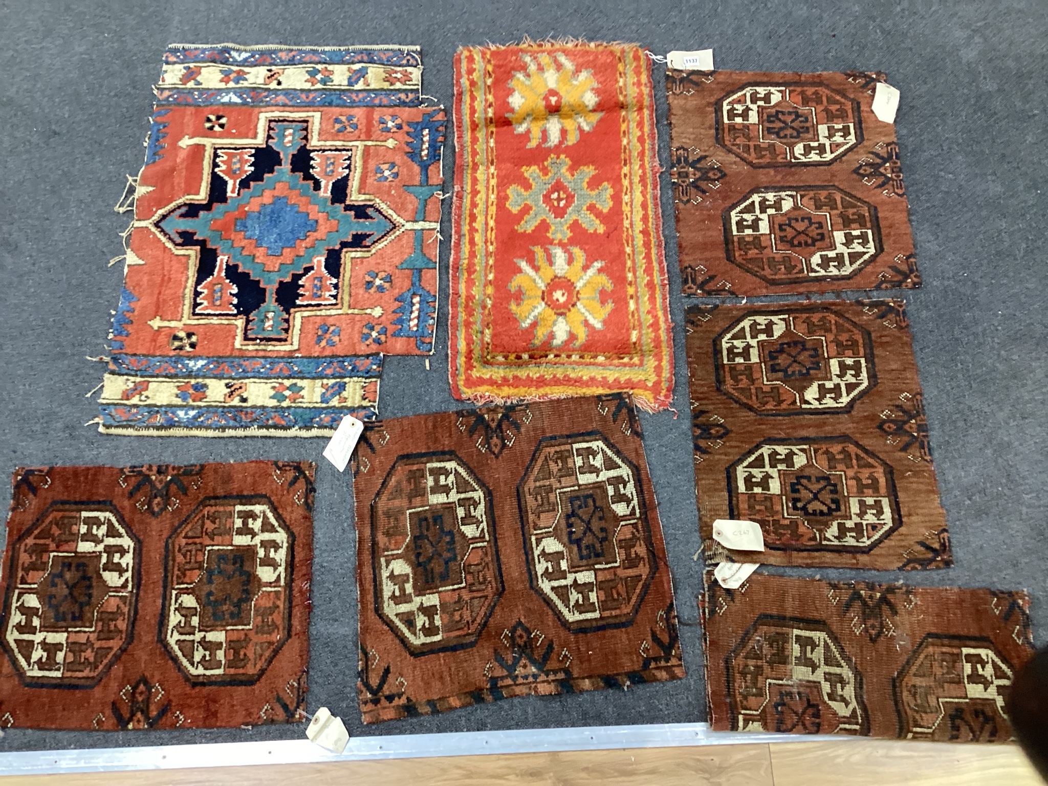 Five antique Afghan carpet fragments, a Caucasian fragment and a Turkish mat, largest 86cms x 58cms.